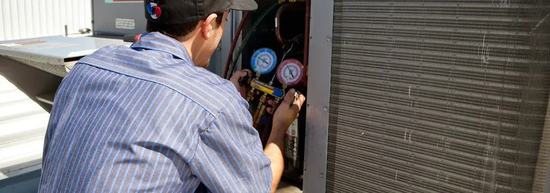 HVAC technician servicing a condenser unit in Alfred