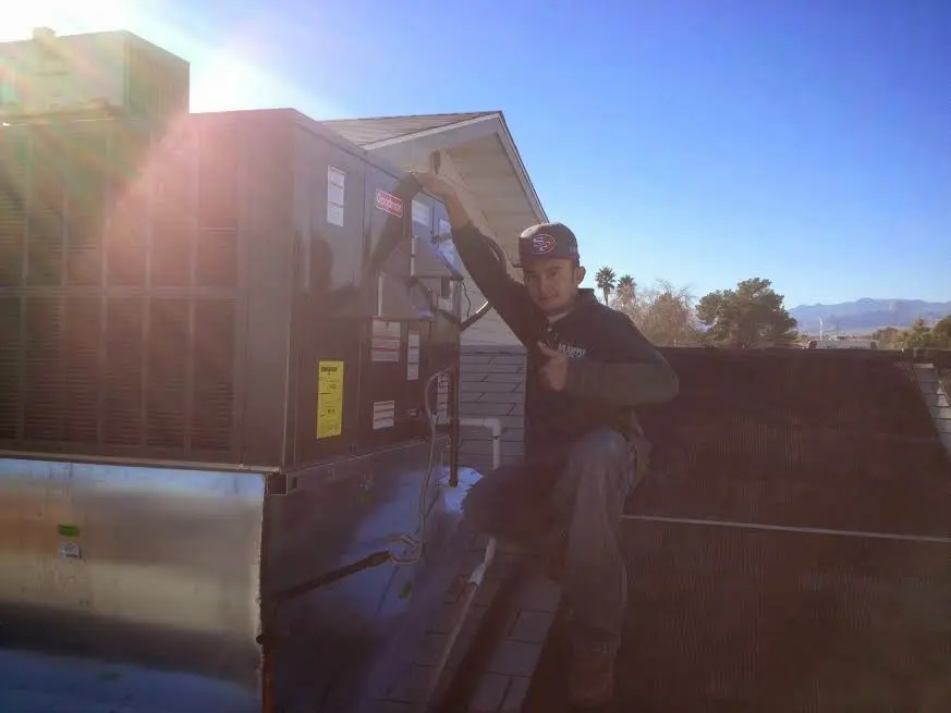HVAC technician performing Heat Pump Repair on a rooftop unit in Alfred